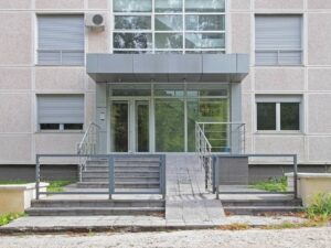 Topographic survey for a raised building entry showing steps, ramp, sidewalk, drainage, and surrounding site elevations.
